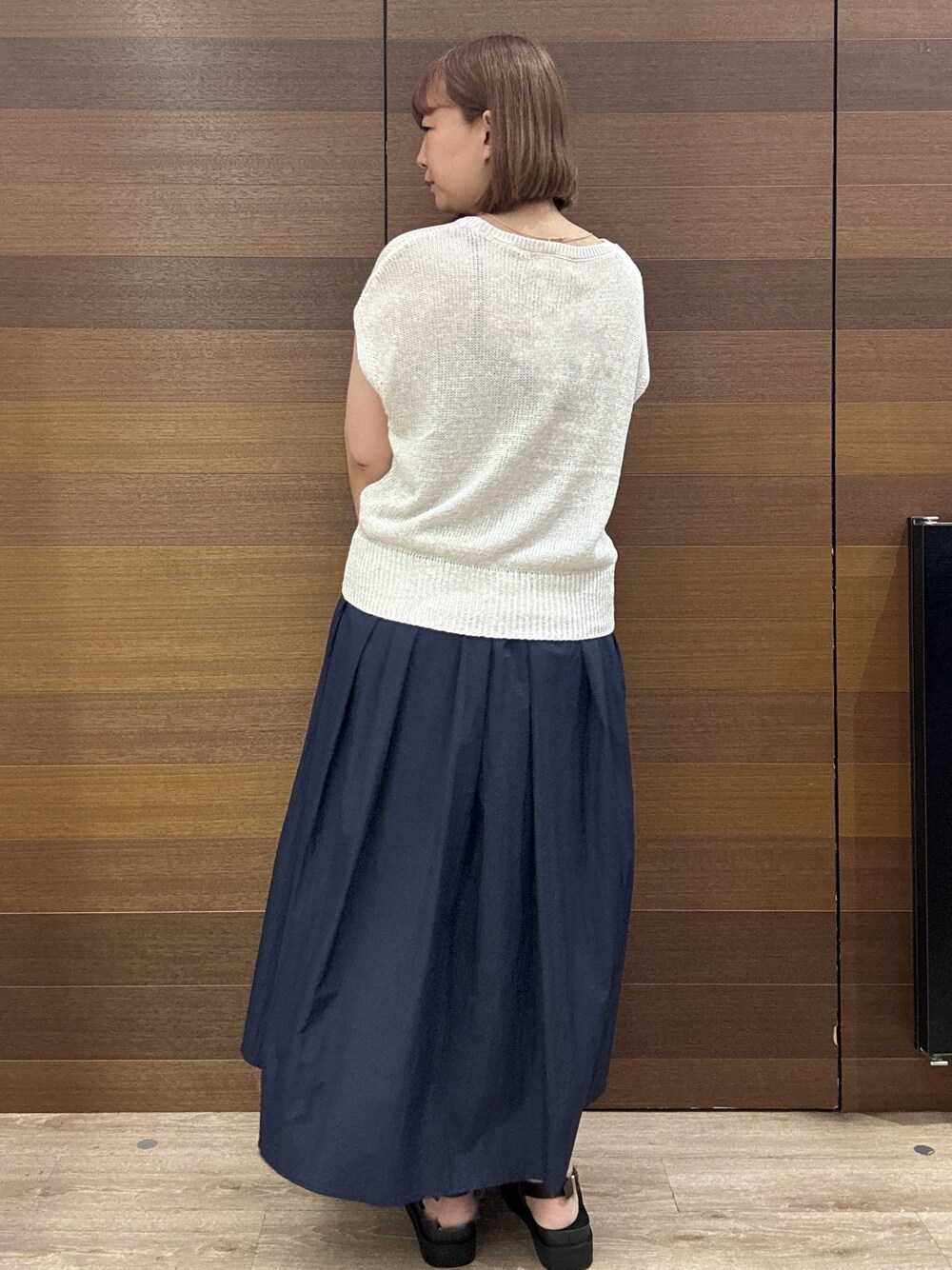 ホワイト系のニット/セーター、ブルー系のスカート、ブラック系のトートバッグを着用したレディースの夏コーディネートの6枚目の写真