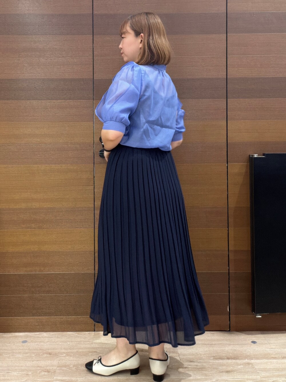 ブルー系のスカート、グレー系のショルダーバッグ、ベージュ系のパンプスを着用したレディースの夏コーディネートの6枚目の写真