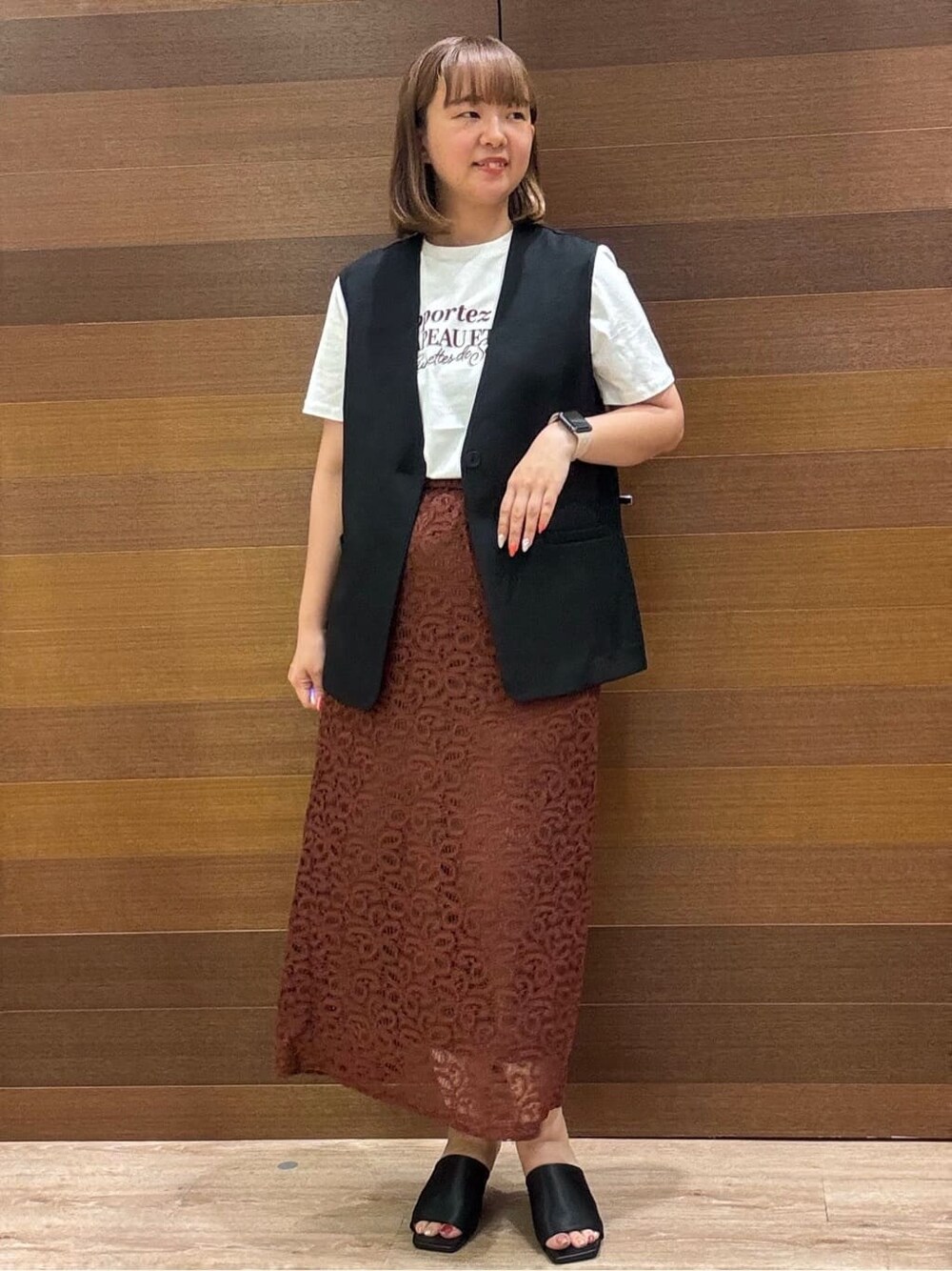 ブラック系のベスト、ホワイト系のTシャツ/カットソー、ブラウン系のスカートを着用したレディースの夏コーディネートの3枚目の写真