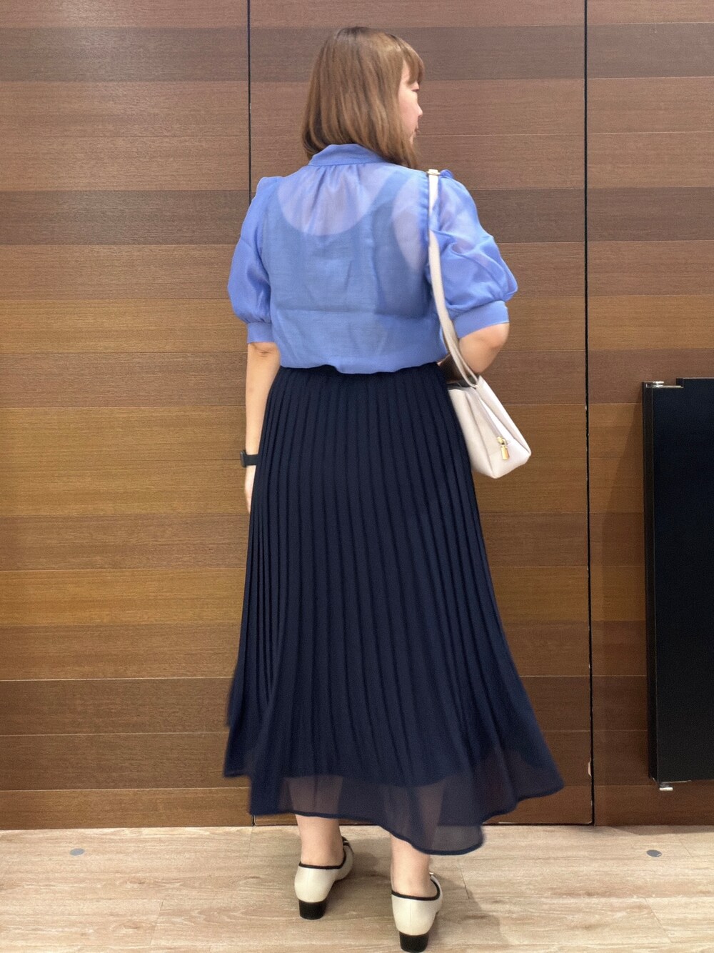 ブルー系のスカート、グレー系のショルダーバッグ、ベージュ系のパンプスを着用したレディースの夏コーディネートの5枚目の写真