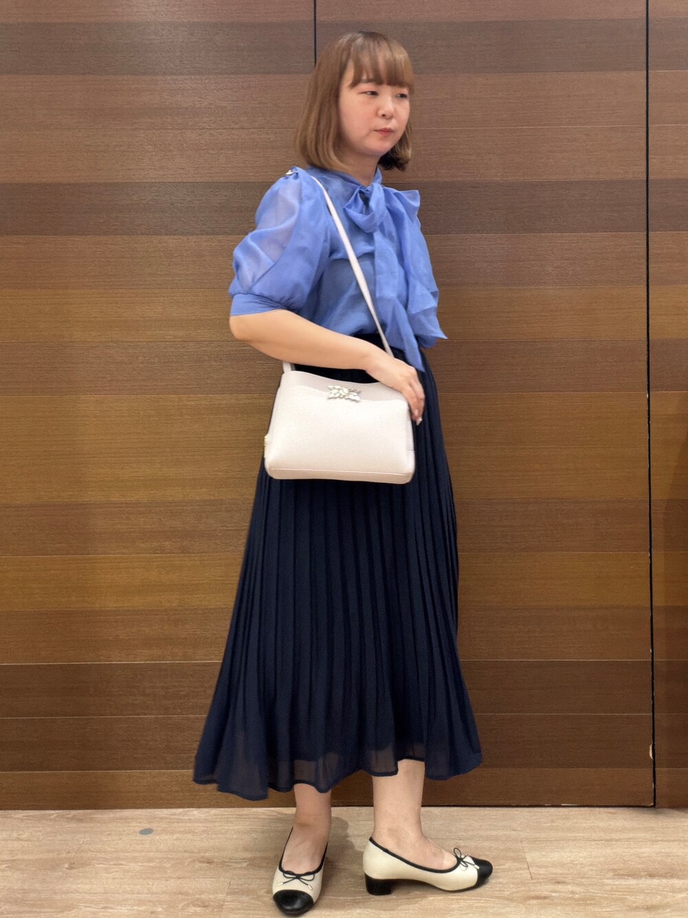 ブルー系のスカート、グレー系のショルダーバッグ、ベージュ系のパンプスを着用したレディースの夏コーディネートの3枚目の写真