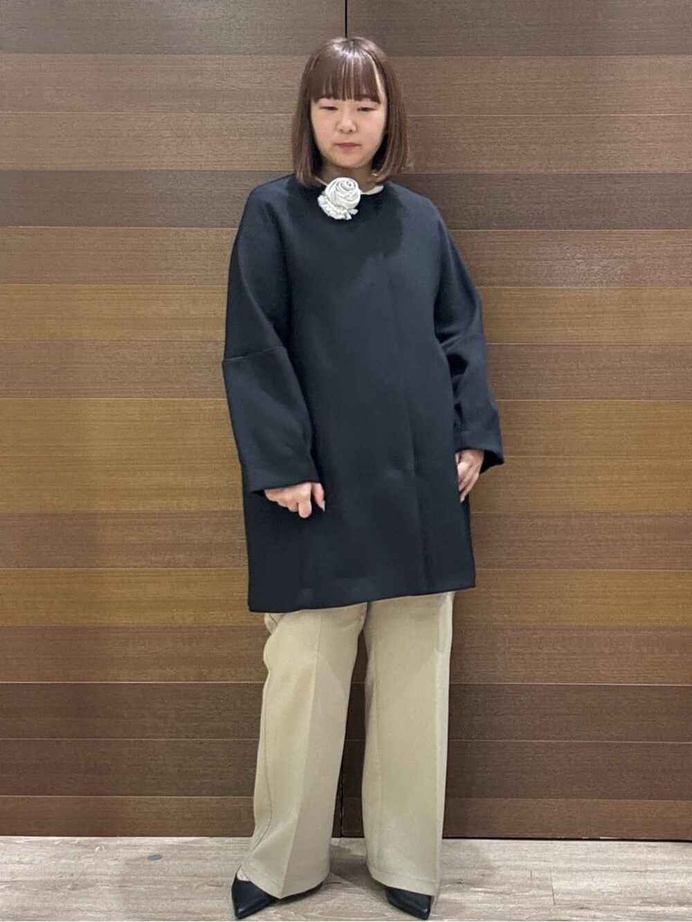 ブラック系のノーカラーコート、ベージュ系のその他パンツ、ホワイト系のハンドバッグを着用したレディースの冬コーディネートの5枚目の写真