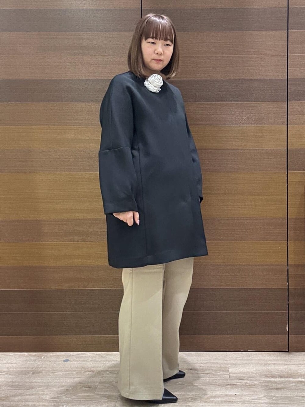 ブラック系のノーカラーコート、ベージュ系のその他パンツ、ホワイト系のハンドバッグを着用したレディースの冬コーディネートの7枚目の写真