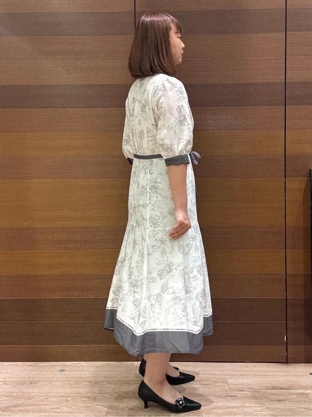 グレー系のワンピース、ベージュ系のショルダーバッグ、ブラック系のパンプスを着用したレディースの夏コーディネートの4枚目の写真