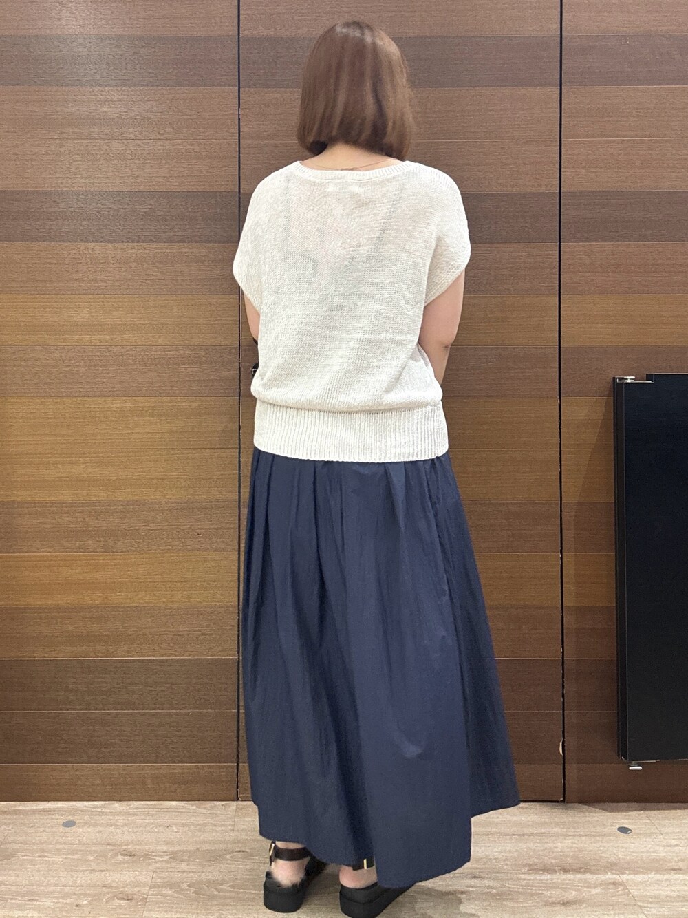ホワイト系のニット/セーター、ブルー系のスカート、ブラック系のトートバッグを着用したレディースの夏コーディネートの7枚目の写真