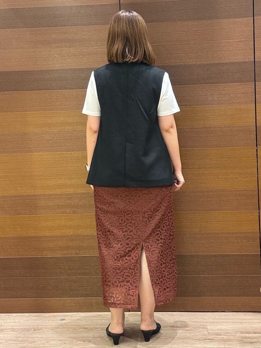 ブラック系のベスト、ホワイト系のTシャツ/カットソー、ブラウン系のスカートを着用したレディースの夏コーディネートの5枚目の写真