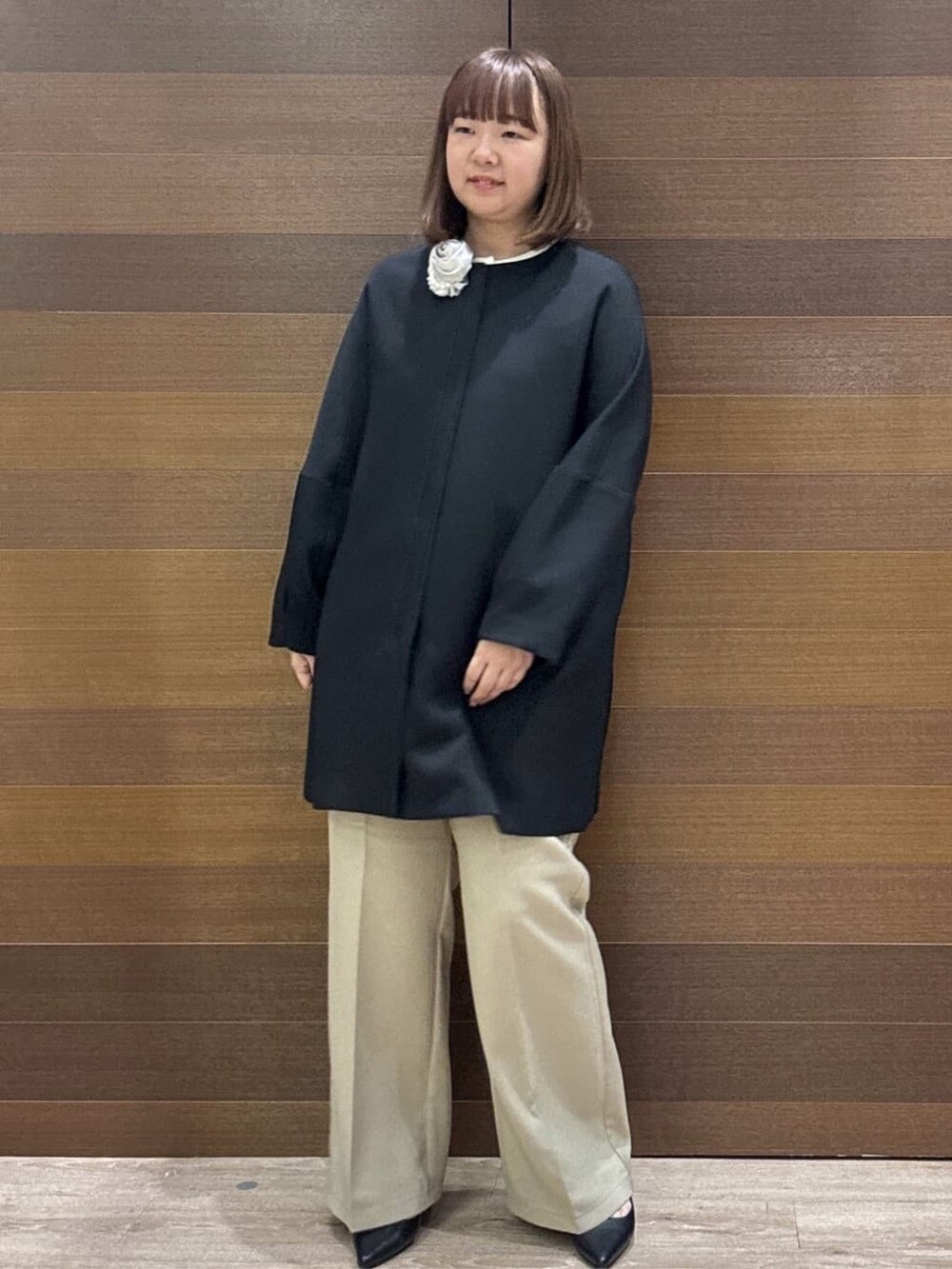 ブラック系のノーカラーコート、ベージュ系のその他パンツ、ホワイト系のハンドバッグを着用したレディースの冬コーディネートの4枚目の写真