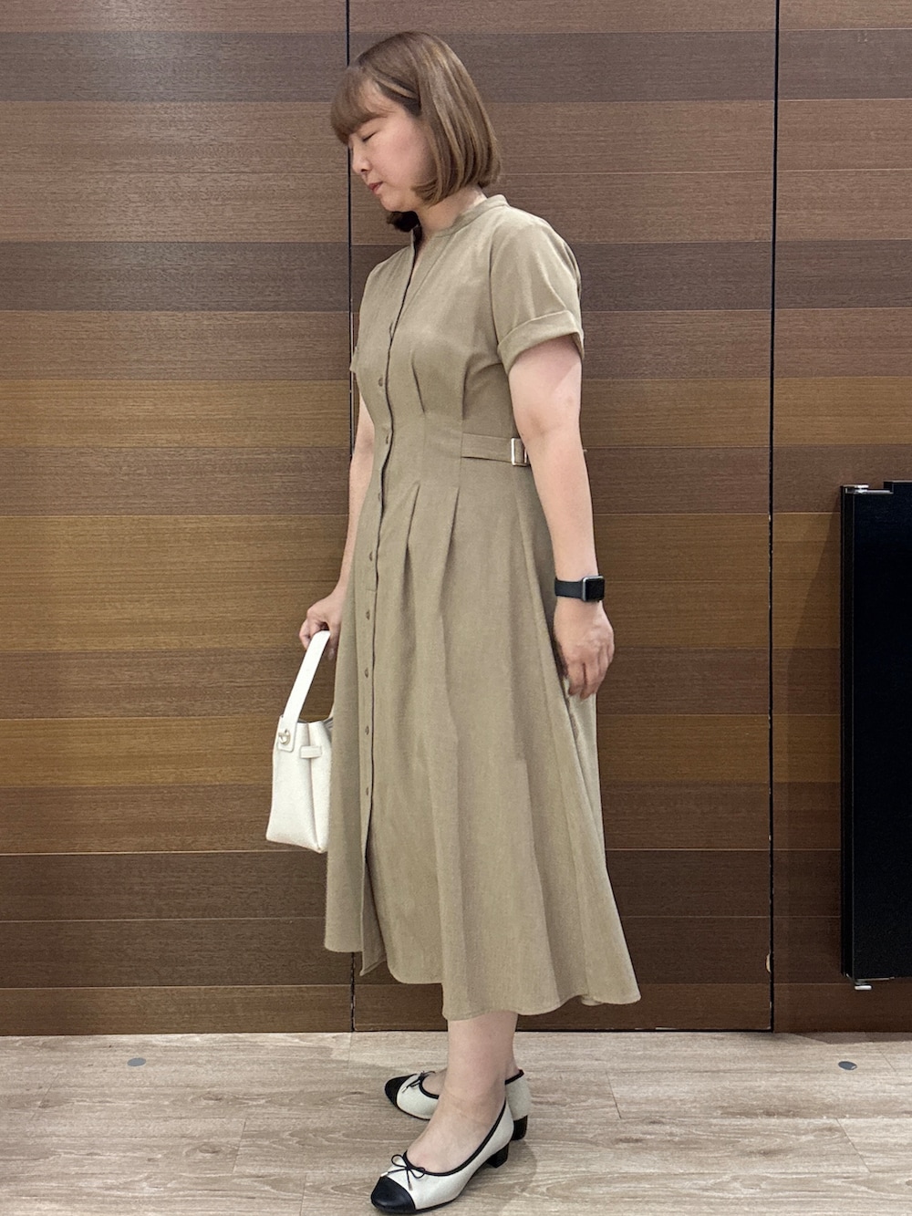 イエロー系のワンピース、ホワイト系のトートバッグ、ベージュ系のパンプスを着用したレディースの夏コーディネートの6枚目の写真