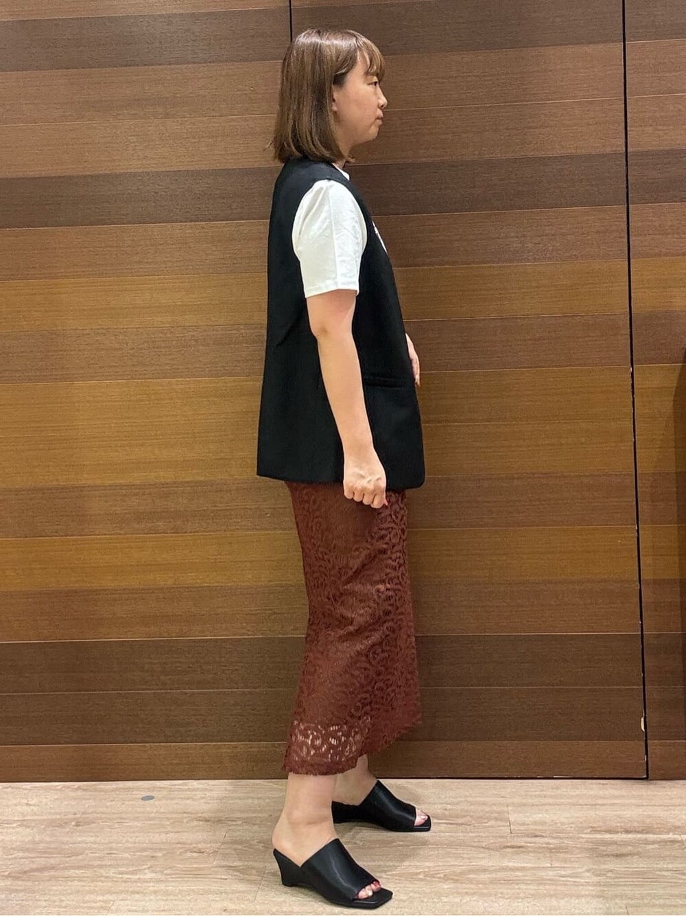 ブラック系のベスト、ホワイト系のTシャツ/カットソー、ブラウン系のスカートを着用したレディースの夏コーディネートの4枚目の写真