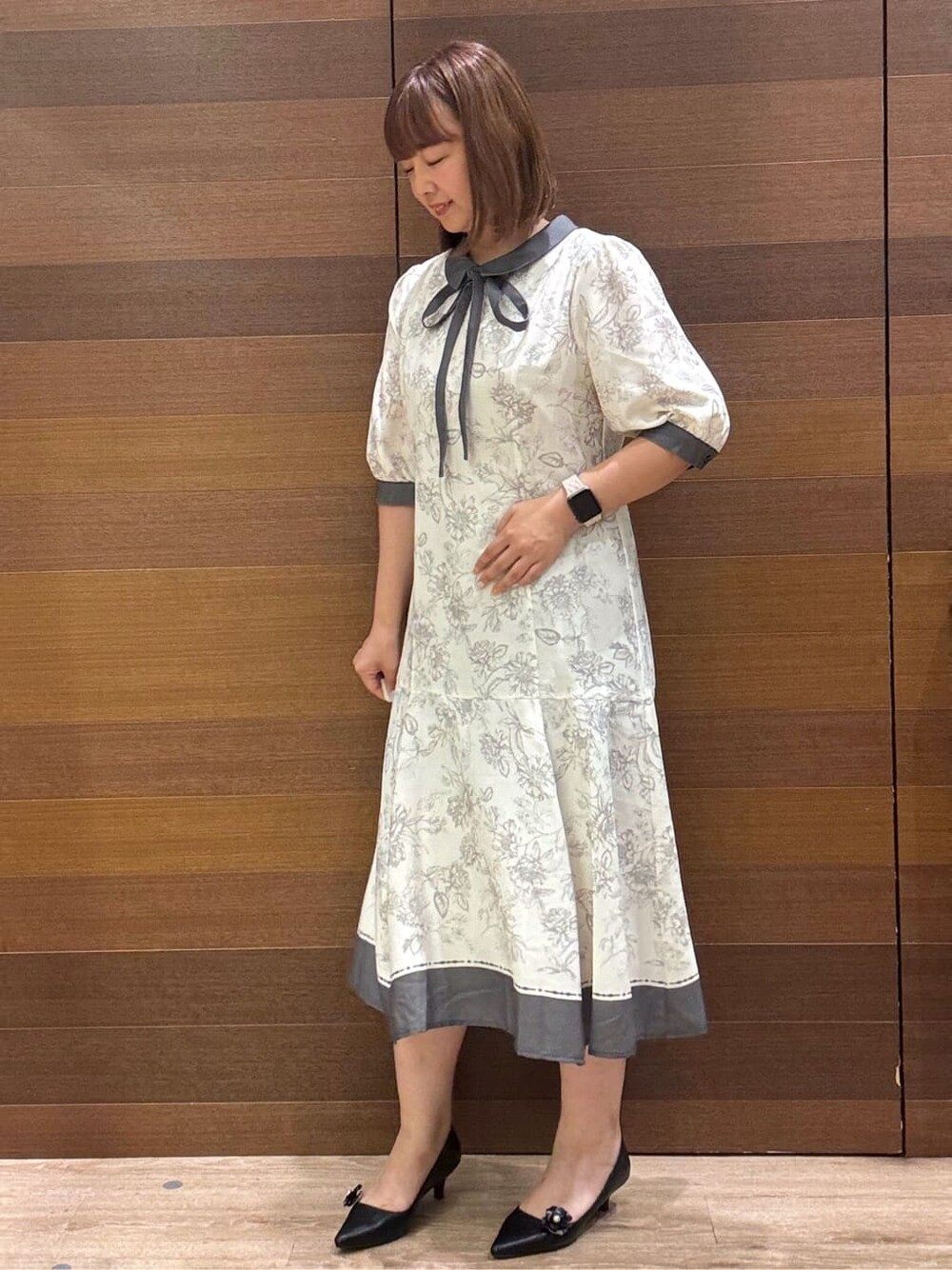 グレー系のワンピース、ベージュ系のショルダーバッグ、ブラック系のパンプスを着用したレディースの夏コーディネートの2枚目の写真