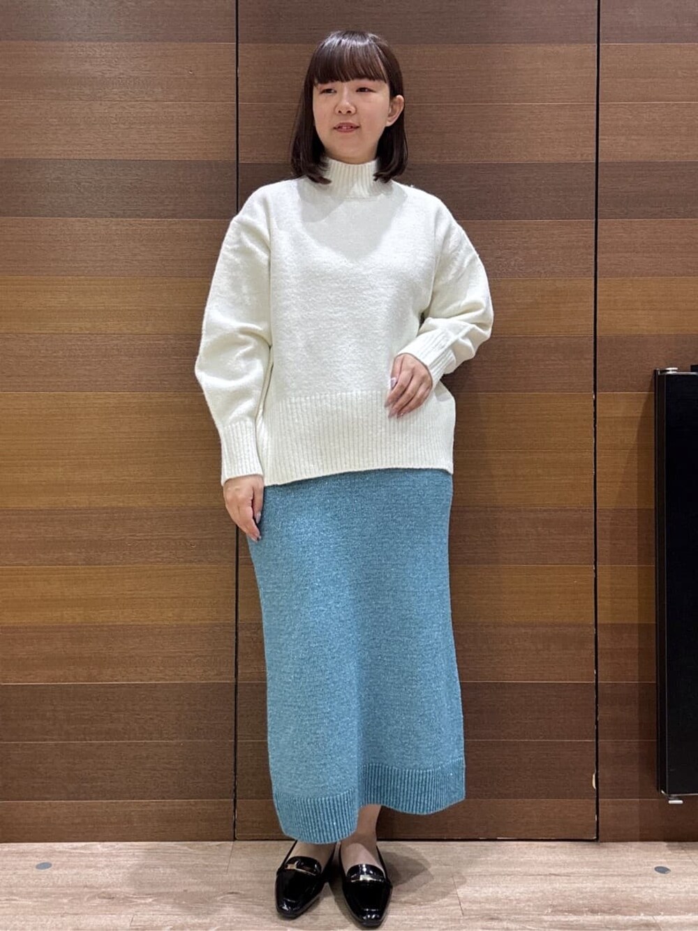 ホワイト系のニット/セーター、ブルー系のスカート、ブラック系のトートバッグを着用したレディースの冬コーディネートの2枚目の写真