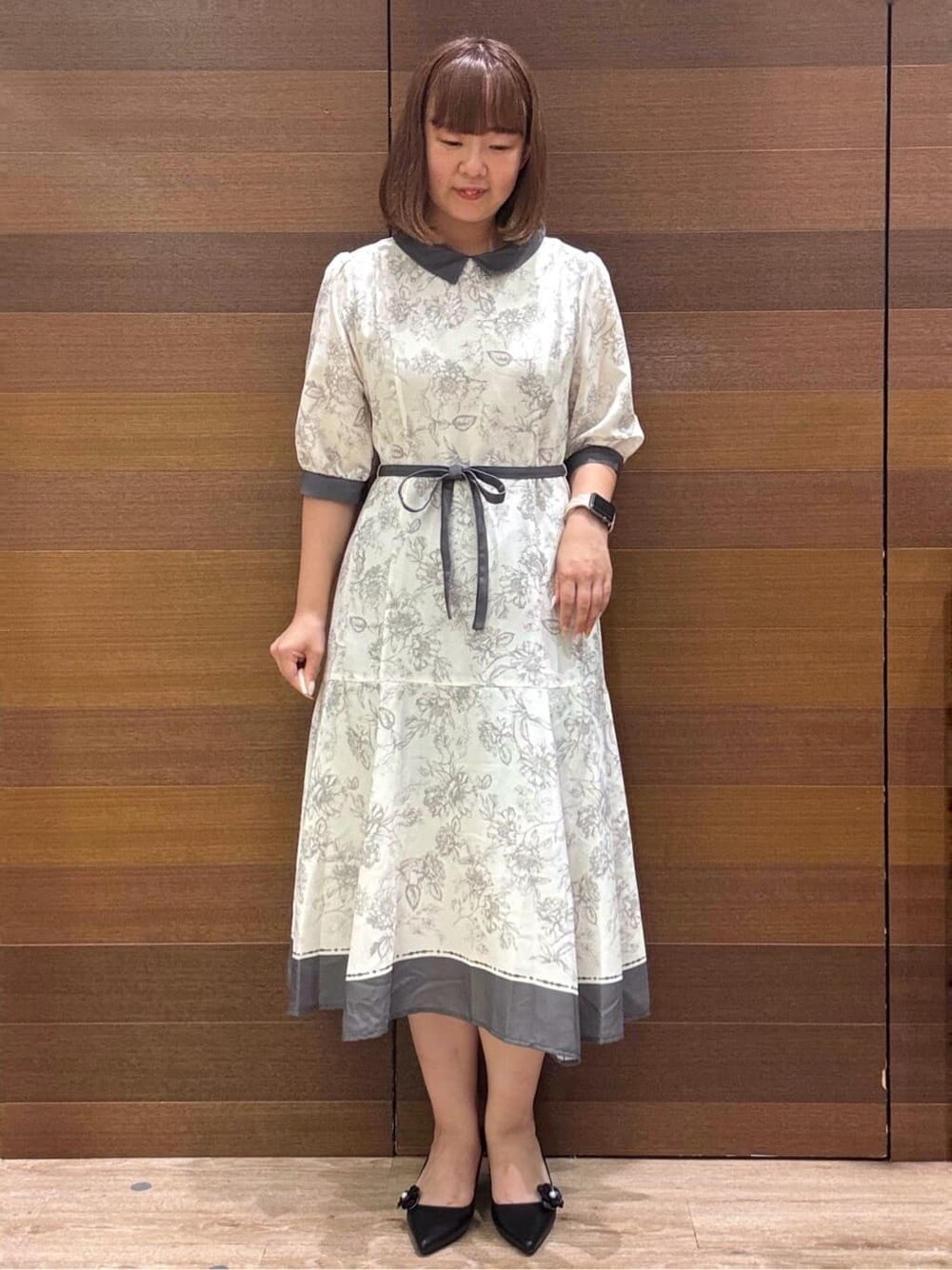 グレー系のワンピース、ベージュ系のショルダーバッグ、ブラック系のパンプスを着用したレディースの夏コーディネートの3枚目の写真