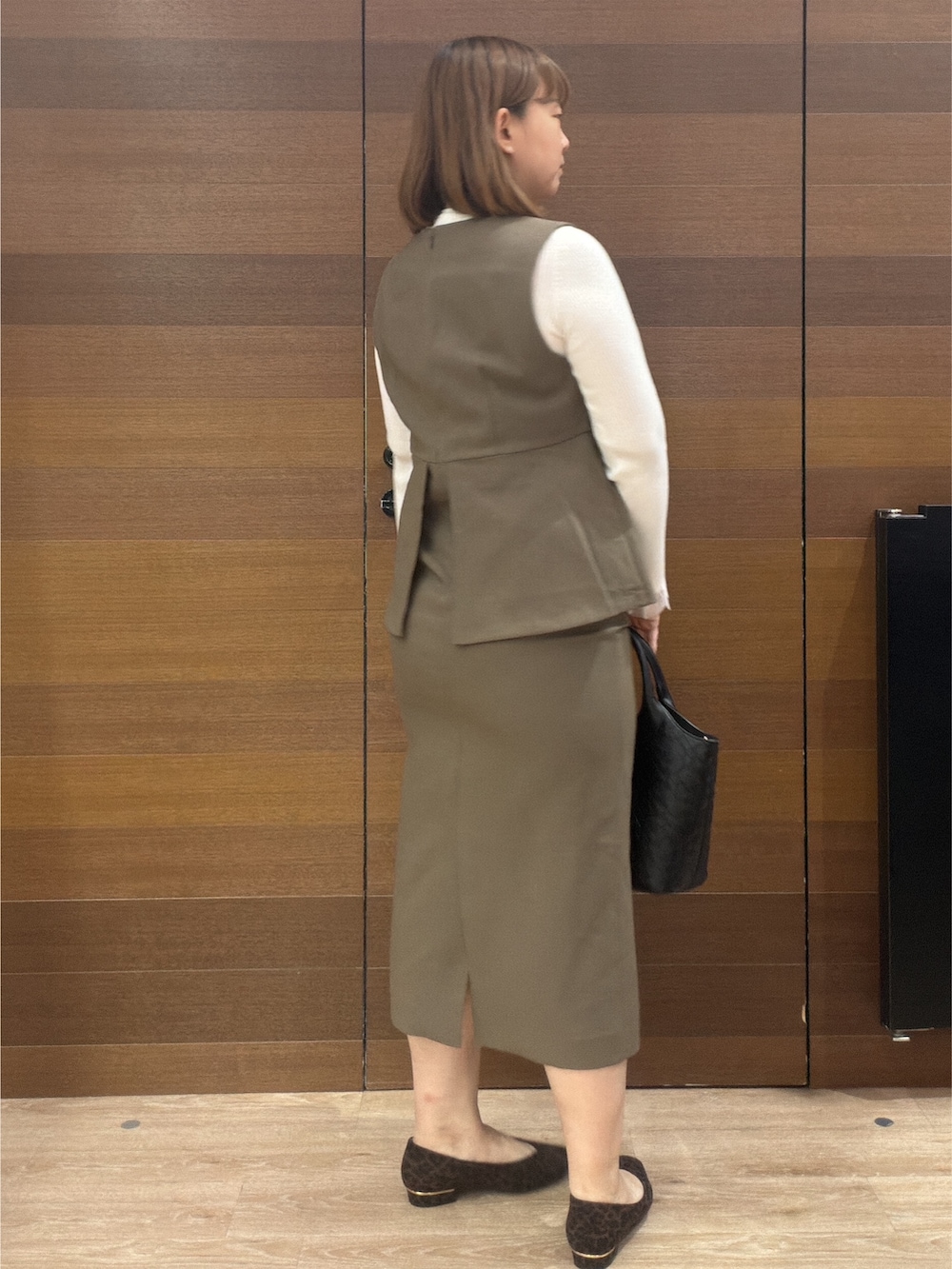 ホワイト系のニット/セーター、ブラウン系のワンピース、ブラック系のトートバッグを着用したレディースの秋コーディネートの4枚目の写真