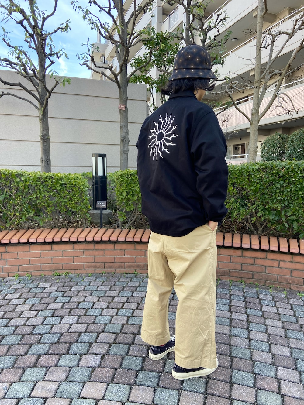 ブラック系のスニーカー、ベージュ系のチノパンツ、ブラック系のジャケット/アウターを着用したメンズの冬コーディネートの2枚目の写真