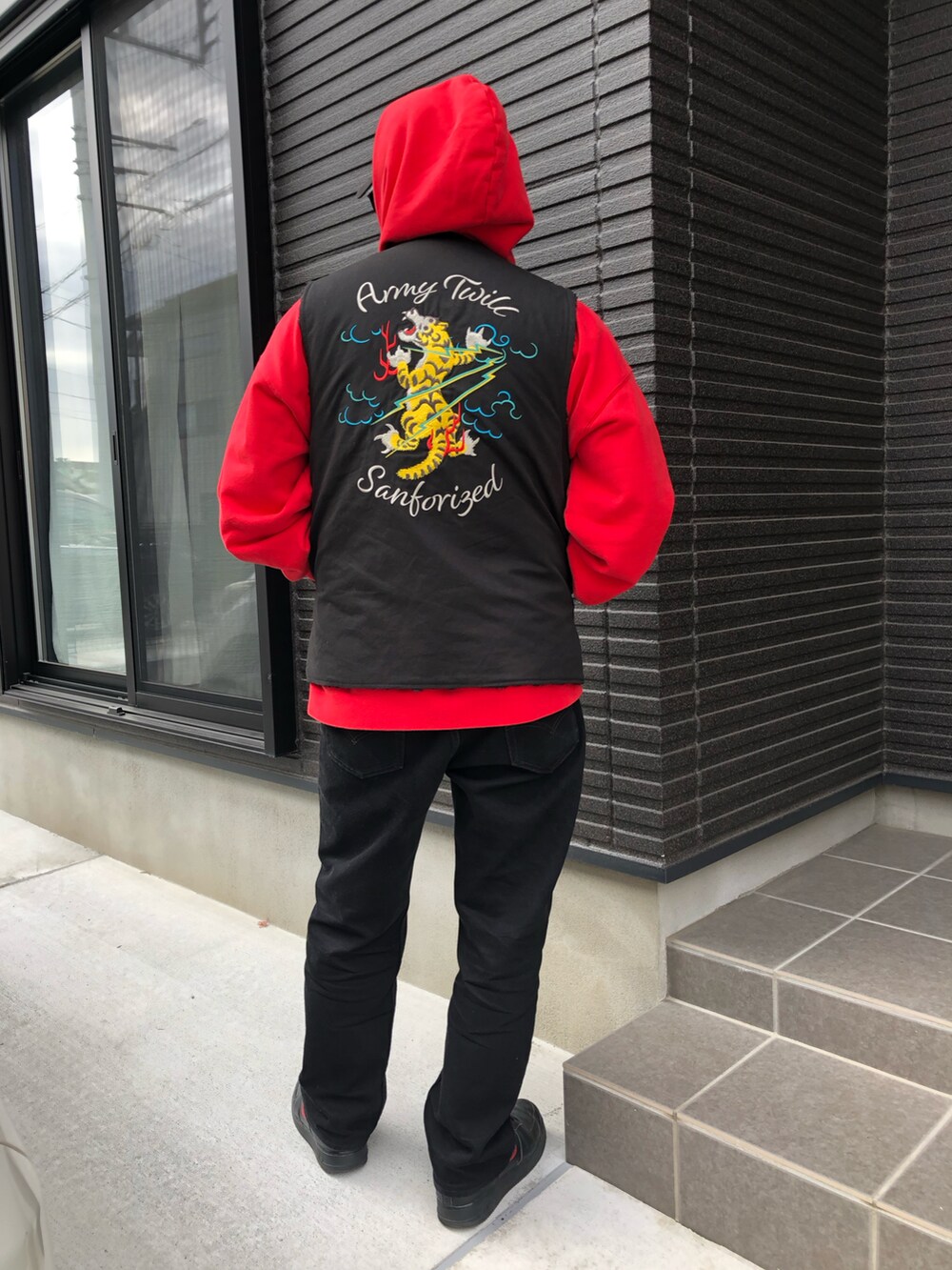 ブラック系のシューズ、レッド系のパーカー、ブラック系のベストを着用したメンズの冬コーディネートの2枚目の写真