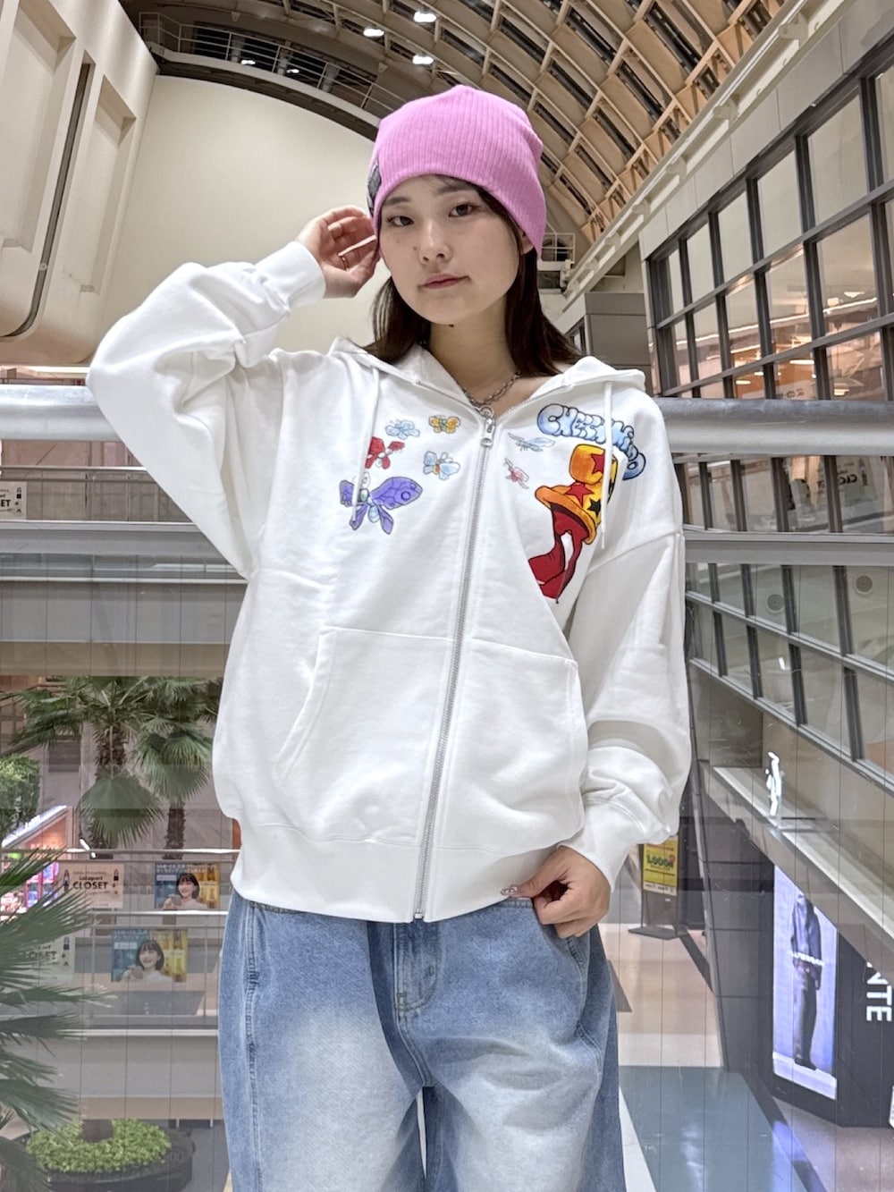 ホワイト系のパーカー、ブルー系のデニムパンツ、ブラック系のショルダーバッグを着用したレディースの冬コーディネートの4枚目の写真