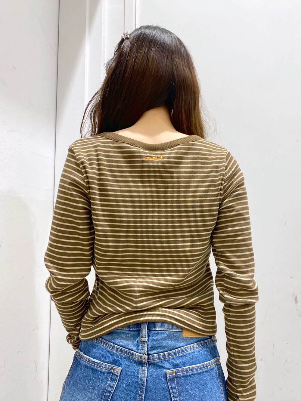 ブラウン系のTシャツ/カットソー、ブルー系のデニムパンツ、ブラック系のショルダーバッグを着用したレディースの冬コーディネートの4枚目の写真