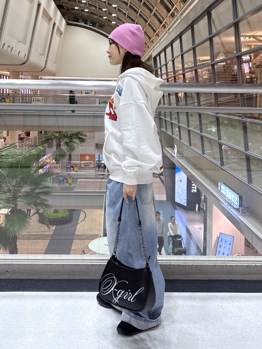 ホワイト系のパーカー、ブルー系のデニムパンツ、ブラック系のショルダーバッグを着用したレディースの冬コーディネートの3枚目の写真