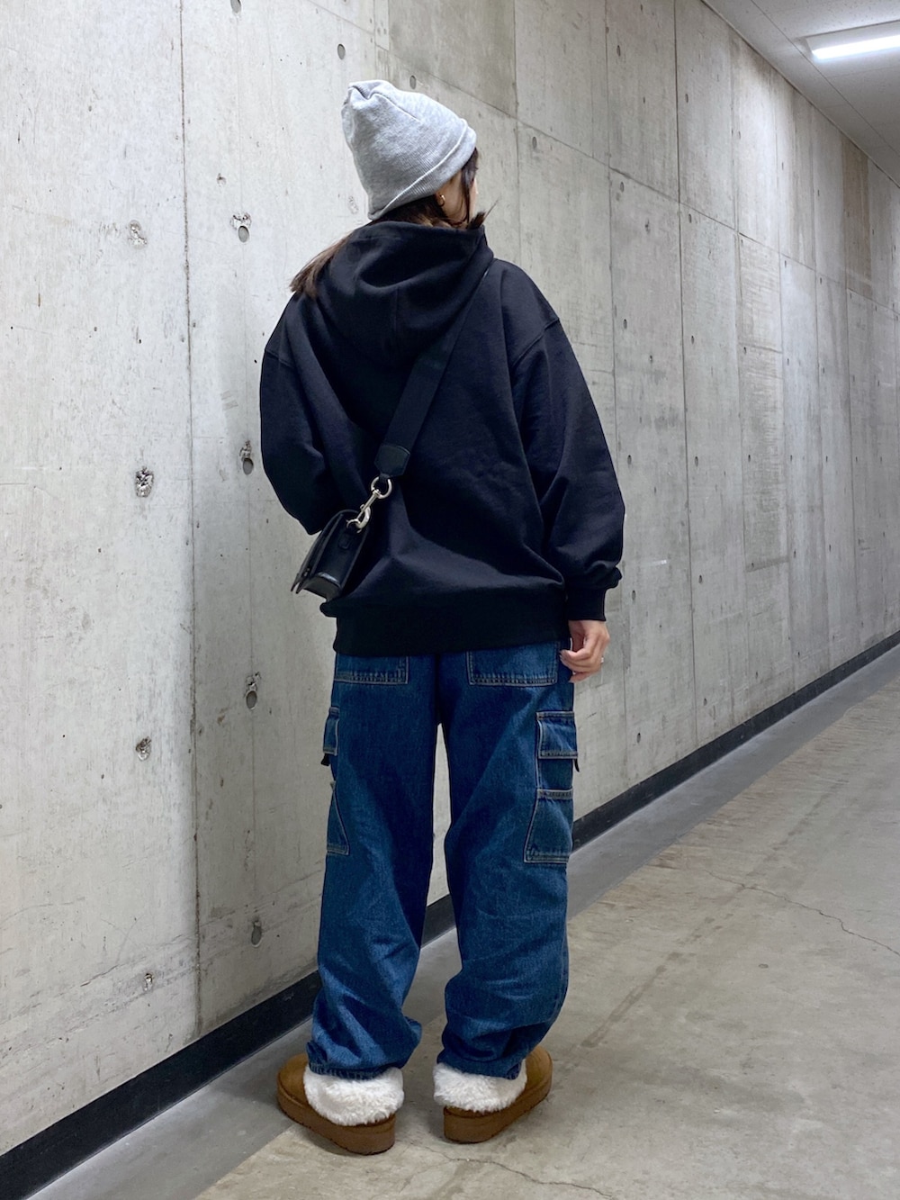 ブラック系のパーカー、ブルー系のカーゴパンツ、ブラック系のショルダーバッグを着用したレディースの冬コーディネートの4枚目の写真