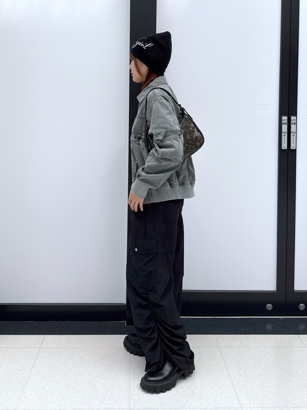 ブラック系のカーゴパンツ、ゴールド系のハンドバッグ、ブラック系のTシャツ/カットソーを着用したレディースの秋コーディネートの2枚目の写真