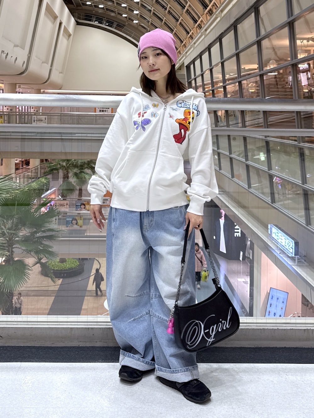 ホワイト系のパーカー、ブルー系のデニムパンツ、ブラック系のショルダーバッグを着用したレディースの冬コーディネートの2枚目の写真