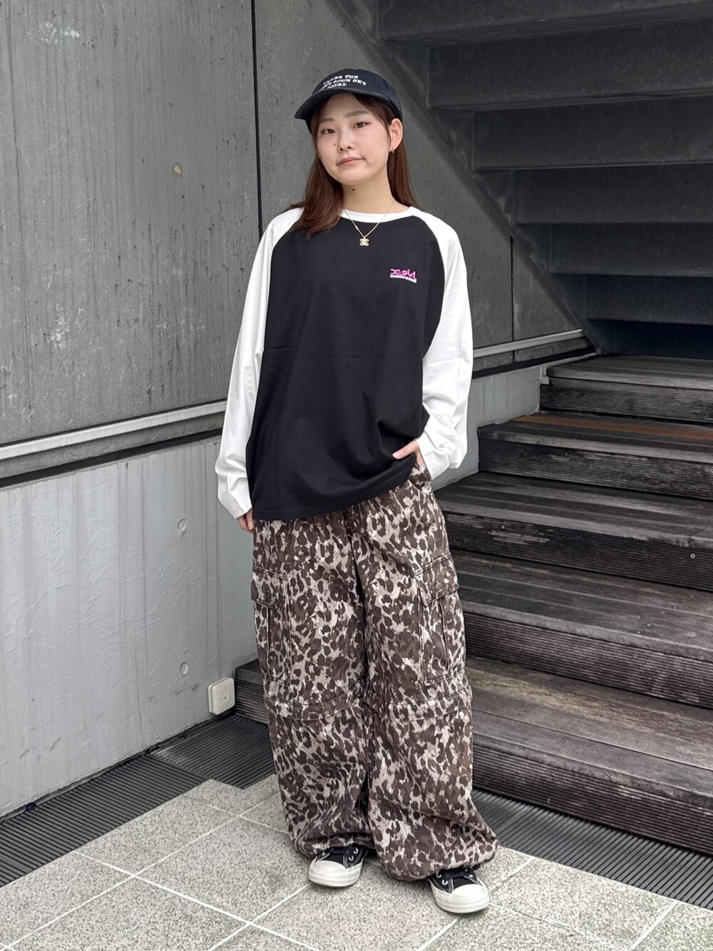 ブラック系のTシャツ/カットソー、ベージュ系のカーゴパンツ、ブラック系のキャップを着用したレディースの秋コーディネートの2枚目の写真
