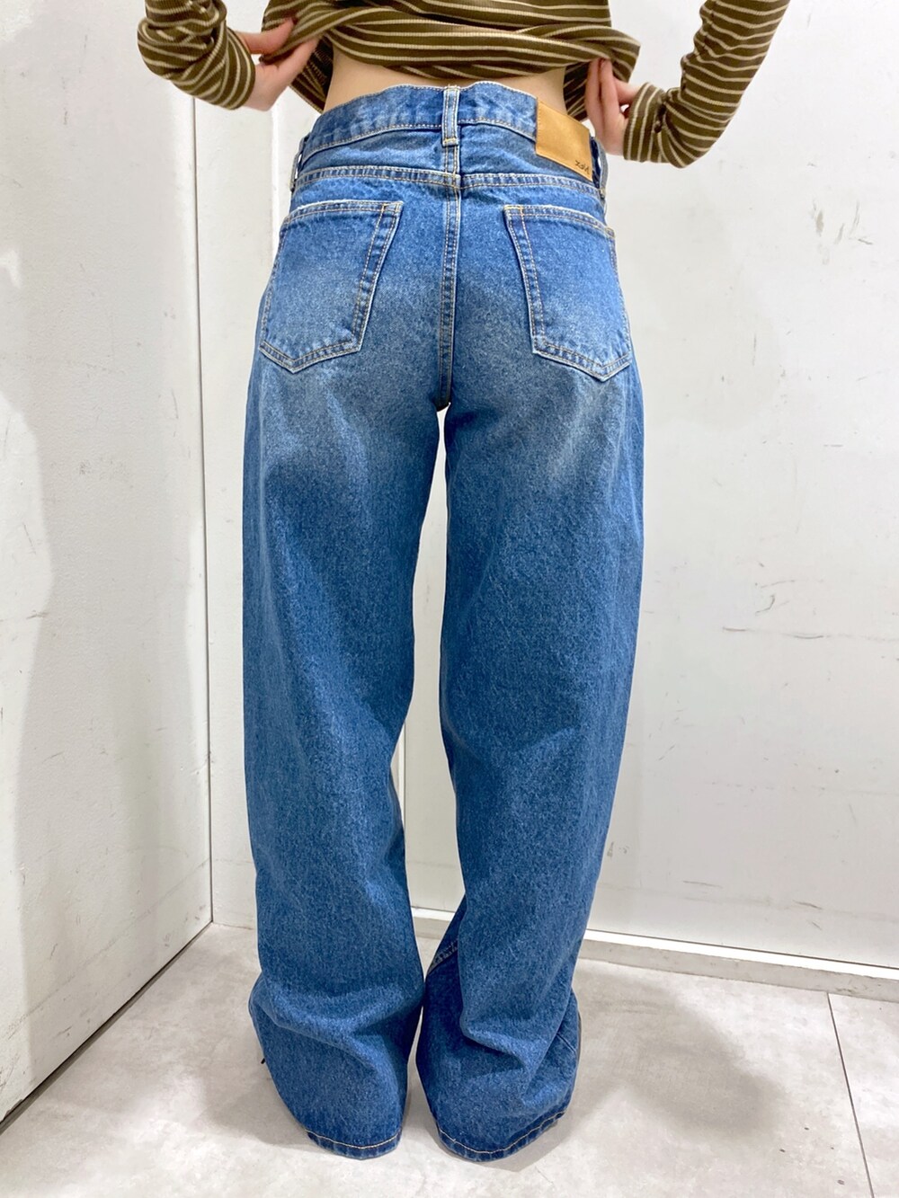 ブラウン系のTシャツ/カットソー、ブルー系のデニムパンツ、ブラック系のショルダーバッグを着用したレディースの冬コーディネートの7枚目の写真