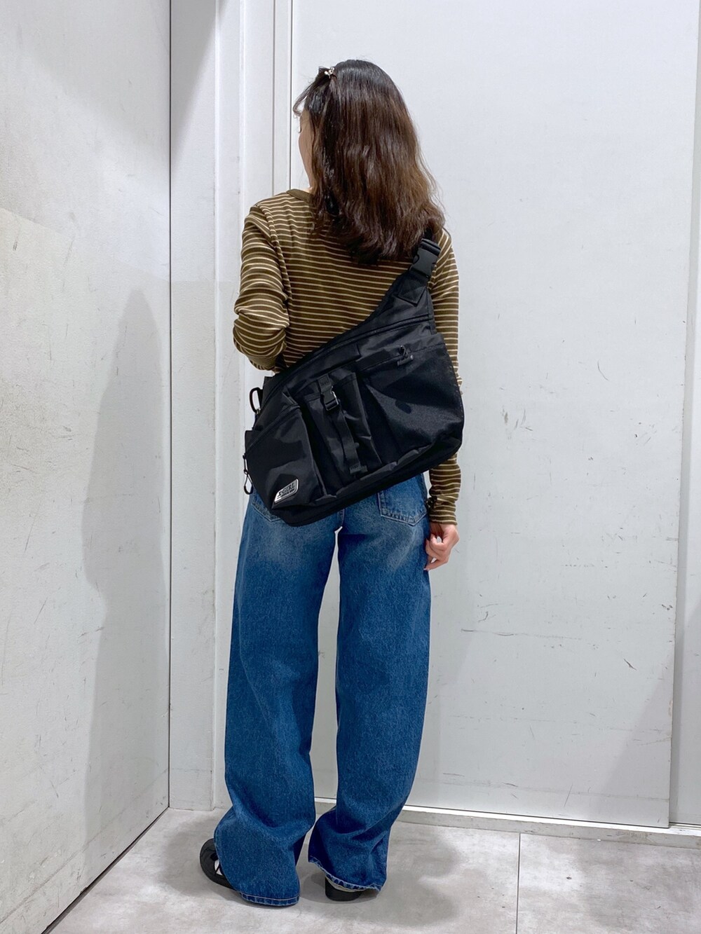 ブラウン系のTシャツ/カットソー、ブルー系のデニムパンツ、ブラック系のショルダーバッグを着用したレディースの冬コーディネートの2枚目の写真