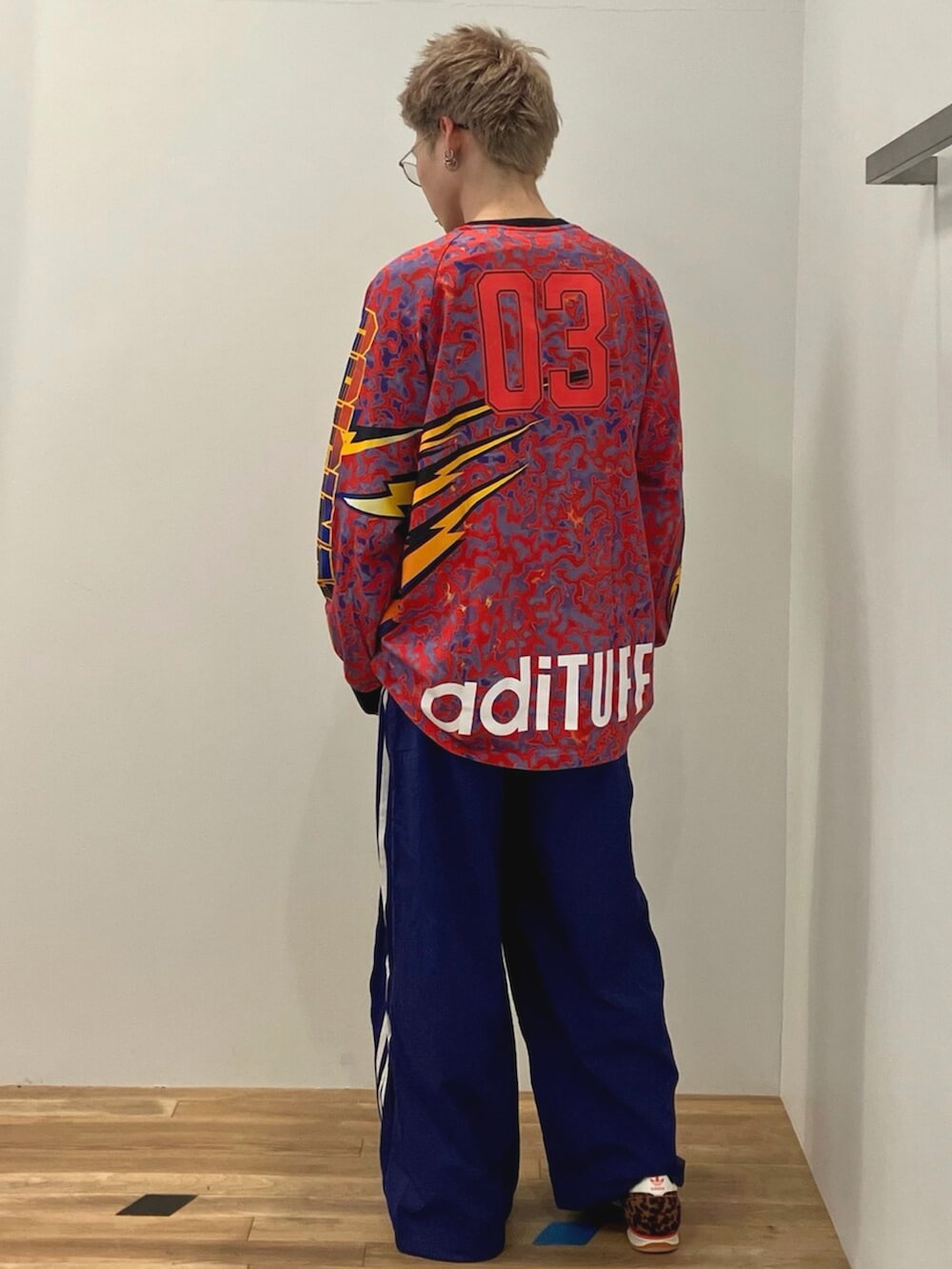 レッド系のTシャツ/カットソー、ブルー系のスウェットパンツ、ブラウン系のスニーカーを着用したメンズの冬コーディネートの3枚目の写真