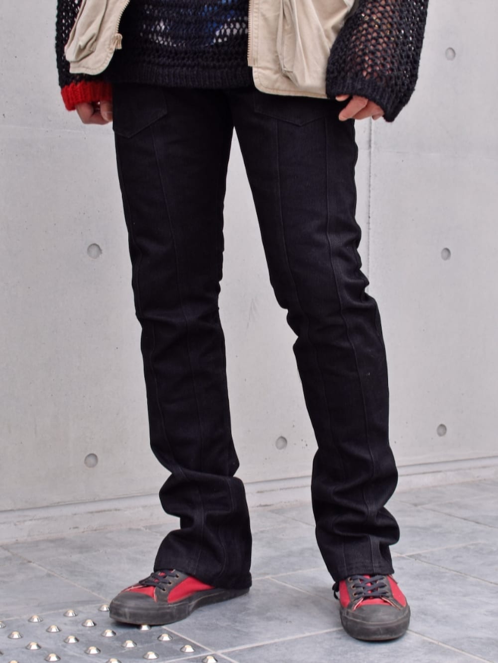 ブラック系のデニムパンツ、ブラック系のニット/セーター、グリーン系のベストを着用したメンズの春コーディネートの3枚目の写真