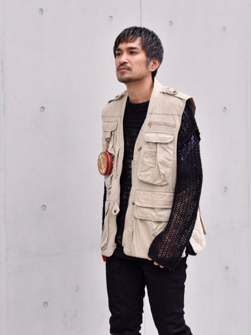 ブラック系のデニムパンツ、ブラック系のニット/セーター、グリーン系のベストを着用したメンズの春コーディネートの2枚目の写真