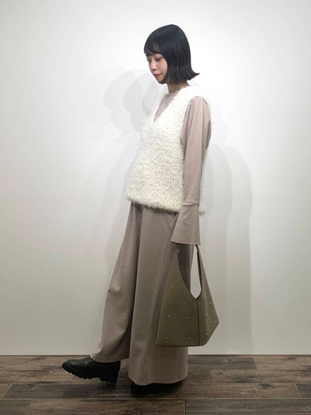 ベージュ系のトートバッグ、ブラウン系のブーツ、ホワイト系のベストを着用したレディースの秋コーディネートの4枚目の写真