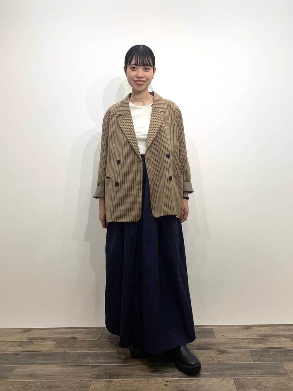 ブラック系のブーツ、ブルー系のスカート、ブラウン系のテーラードジャケットを着用したレディースの秋コーディネートの2枚目の写真