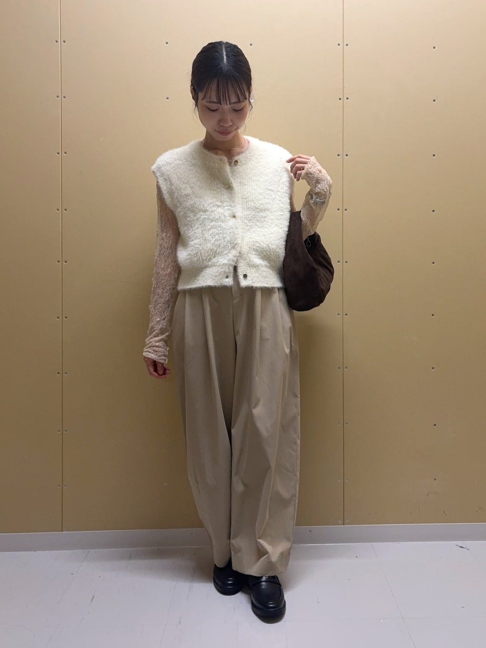 ホワイト系のニット/セーター、ベージュ系のTシャツ/カットソー、ブラウン系のハンドバッグを着用したレディースの秋コーディネートの2枚目の写真