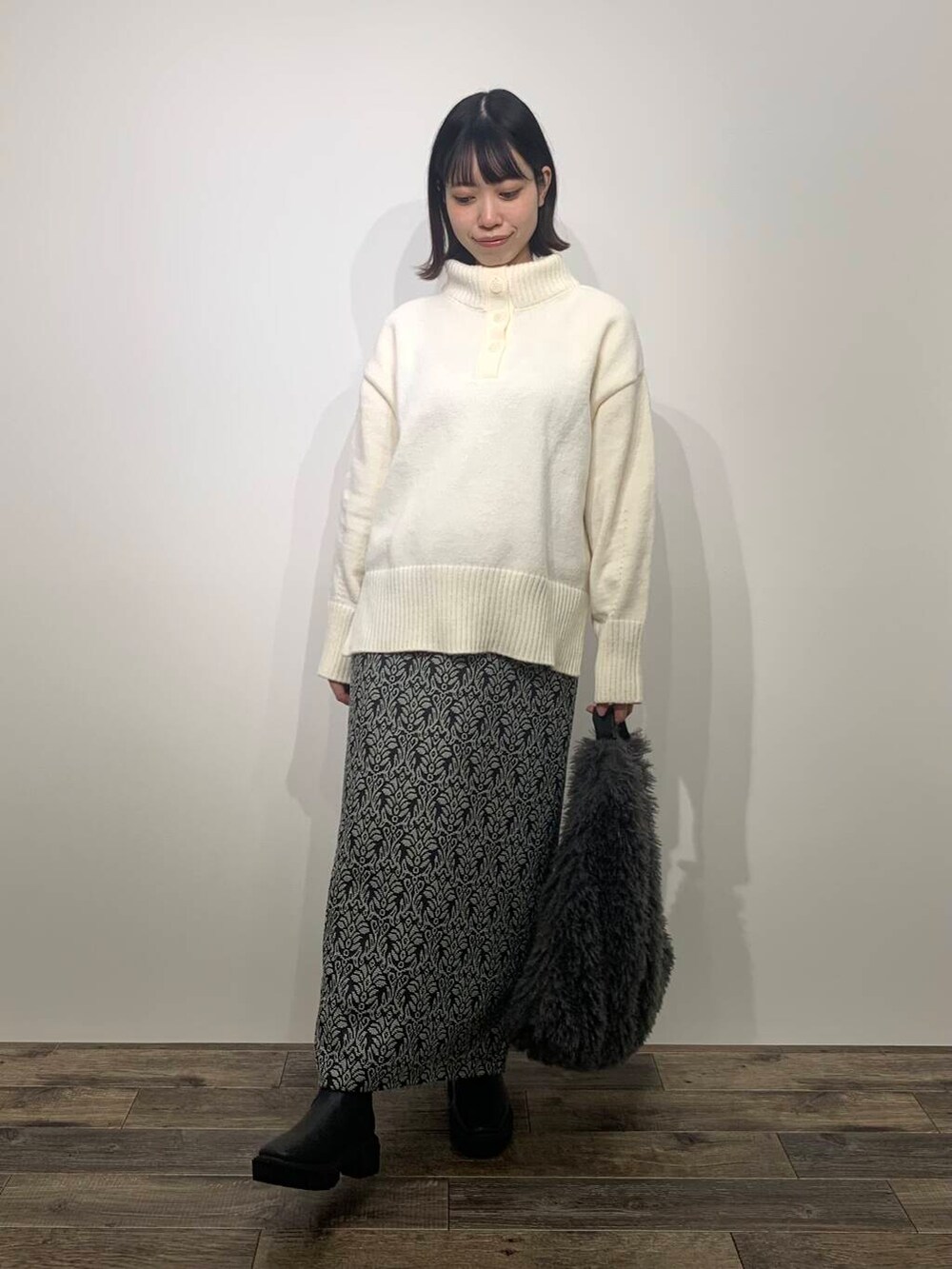 ブラック系のブーツ、グレー系のトートバッグ、ホワイト系のニット/セーターを着用したレディースの秋コーディネートの2枚目の写真