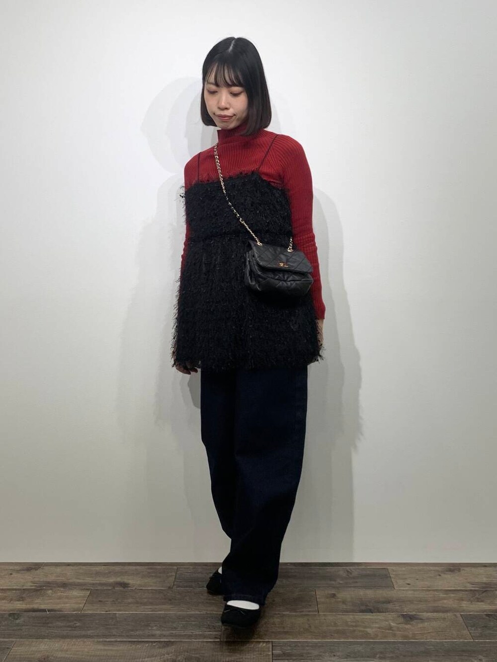 レッド系のニット/セーター、ブラック系のショルダーバッグ、ブルー系のデニムパンツを着用したレディースの冬コーディネートの4枚目の写真