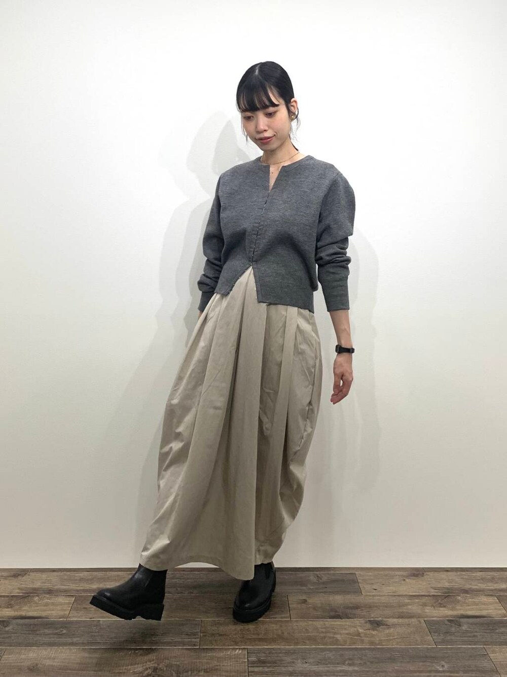 ブラック系のブーツ、ベージュ系のスカート、グレー系のカーディガン/ボレロを着用したレディースの秋コーディネートの3枚目の写真