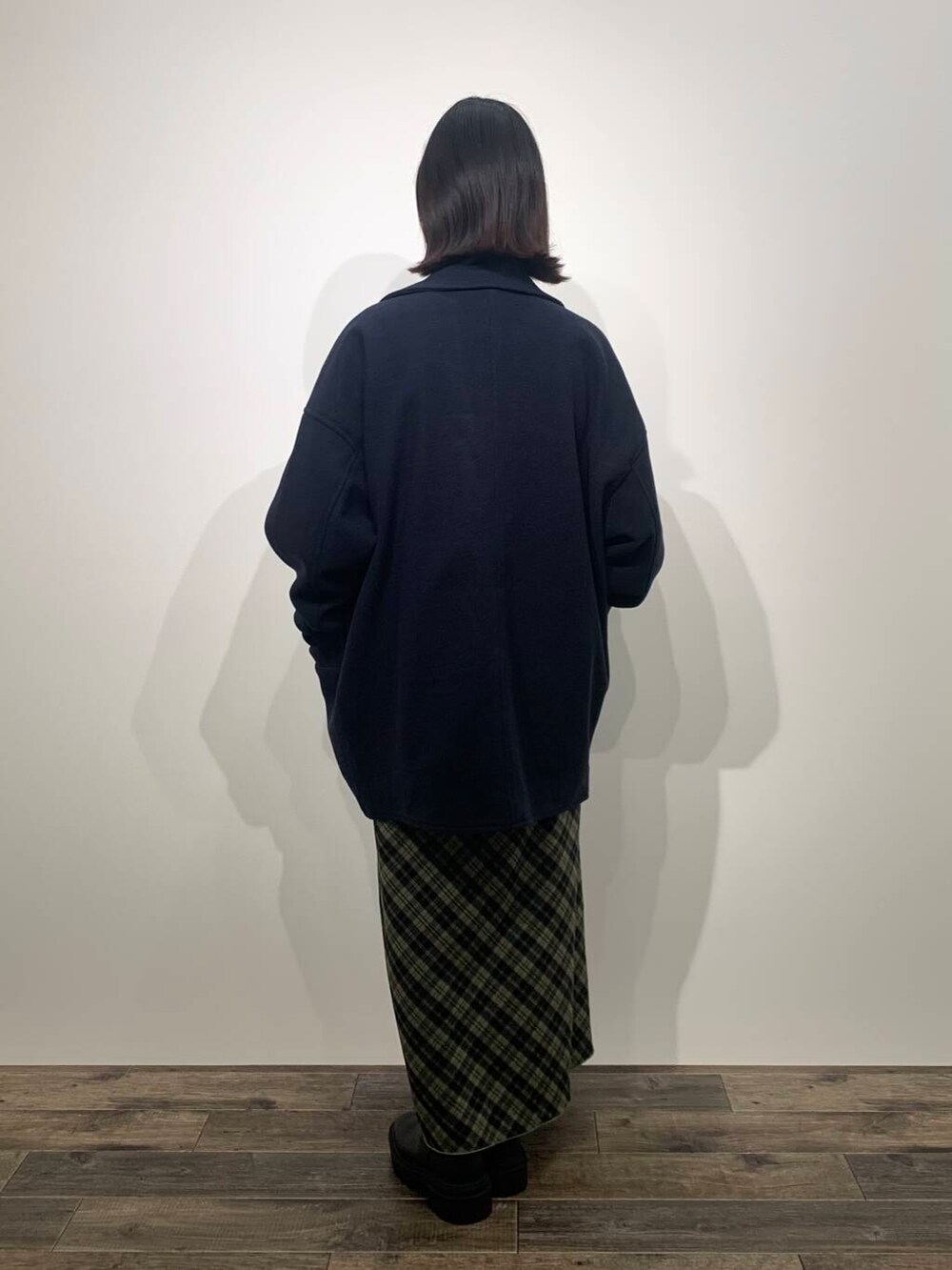 ブルー系のステンカラーコート、ブラック系のブーツ、ホワイト系のTシャツ/カットソーを着用したレディースの秋コーディネートの4枚目の写真