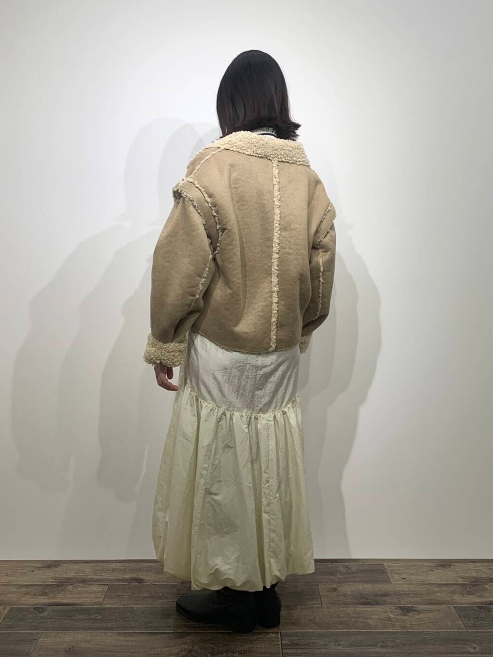 ホワイト系のニット/セーター、ブラック系のブーツ、ホワイト系のスカートを着用したレディースの秋コーディネートの5枚目の写真