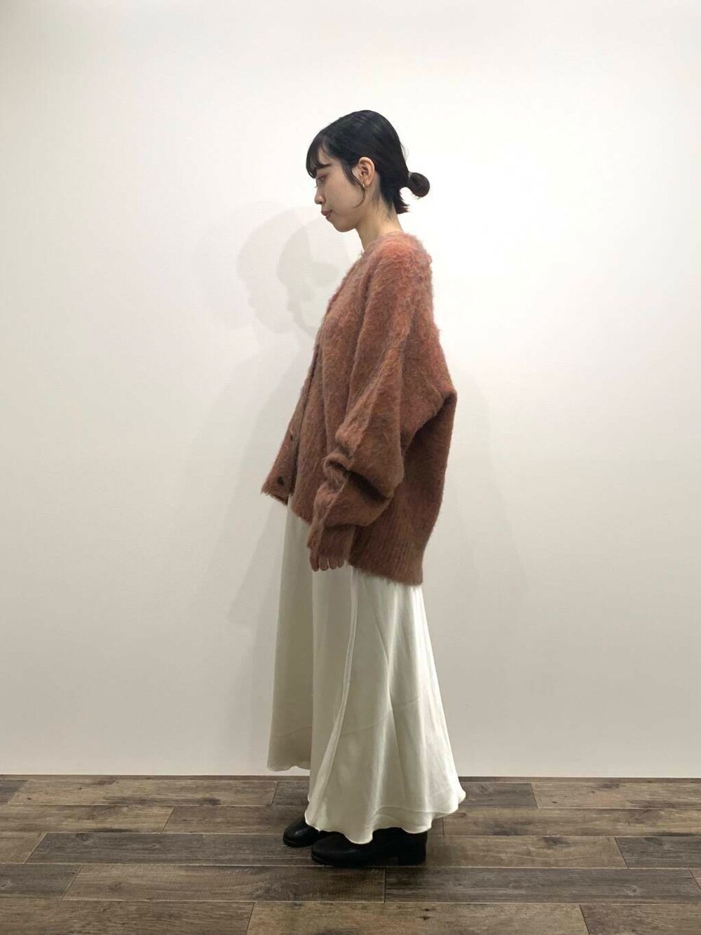 ブラック系のブーツ、ホワイト系のスカート、オレンジ系のカーディガン/ボレロを着用したレディースの秋コーディネートの4枚目の写真