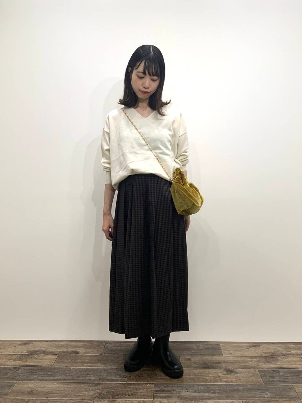 イエロー系のハンドバッグ、ブラック系のブーツ、ホワイト系のニット/セーターを着用したレディースの秋コーディネートの3枚目の写真