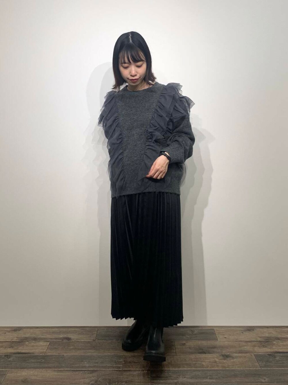 ブラック系のブーツ、グレー系のニット/セーター、ブラック系のスカートを着用したレディースの秋コーディネートの3枚目の写真