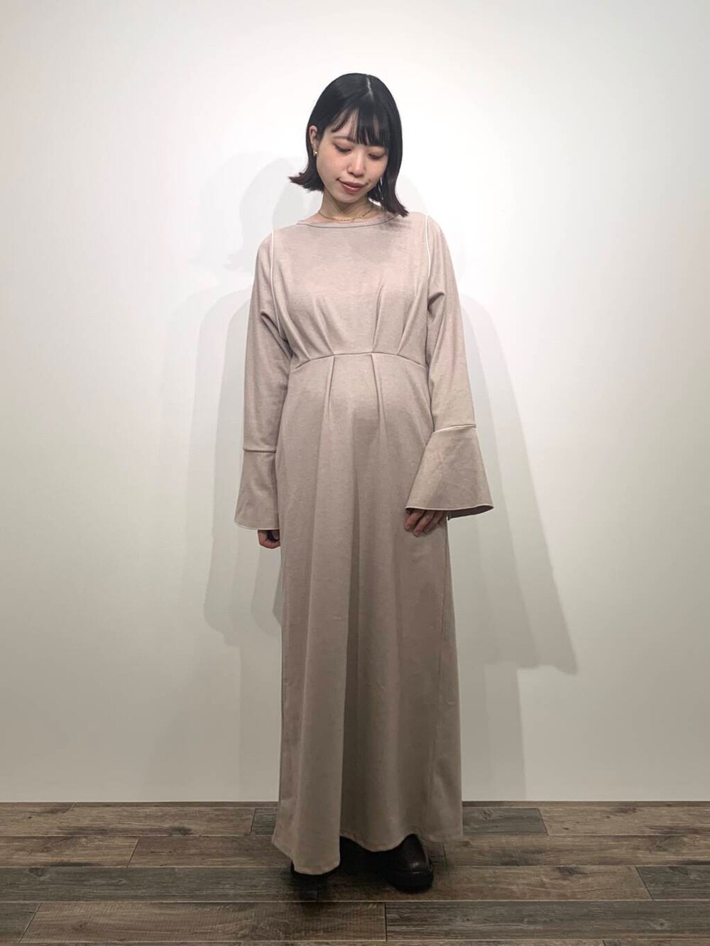 ベージュ系のトートバッグ、ブラウン系のブーツ、ホワイト系のベストを着用したレディースの秋コーディネートの6枚目の写真