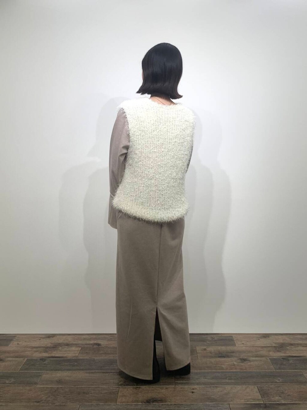 ベージュ系のトートバッグ、ブラウン系のブーツ、ホワイト系のベストを着用したレディースの秋コーディネートの5枚目の写真