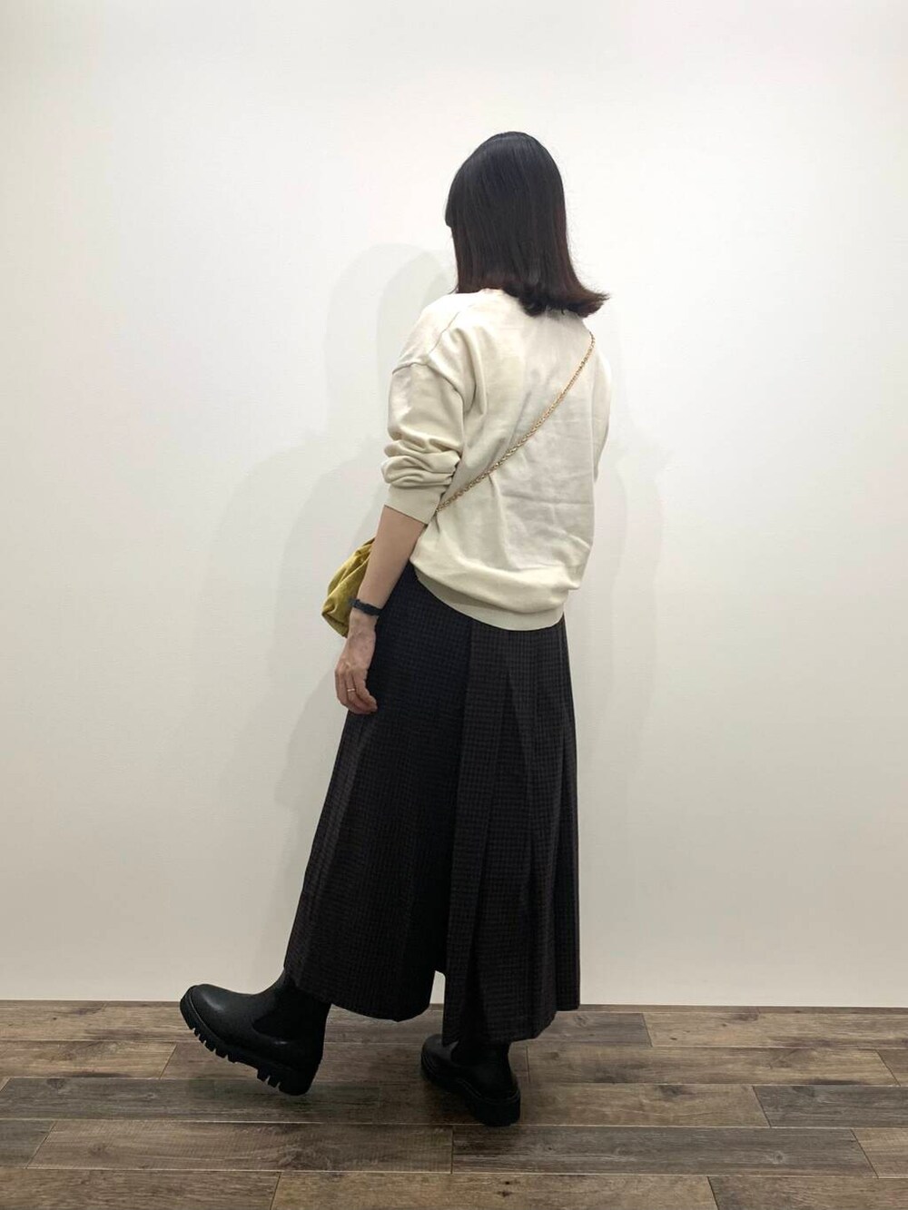 イエロー系のハンドバッグ、ブラック系のブーツ、ホワイト系のニット/セーターを着用したレディースの秋コーディネートの5枚目の写真
