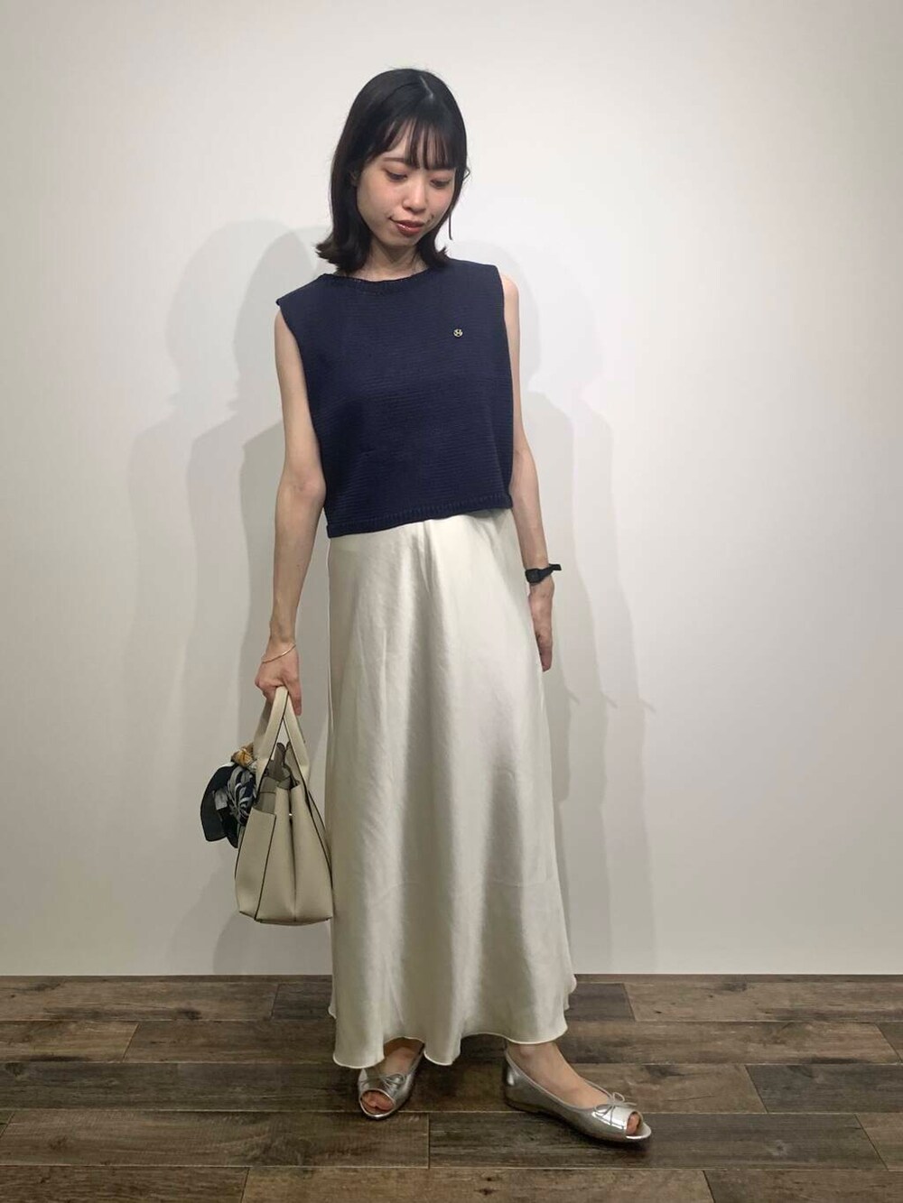 ホワイト系のトートバッグ、シルバー系のパンプス、ブルー系のニット/セーターを着用したレディースの夏コーディネートの2枚目の写真