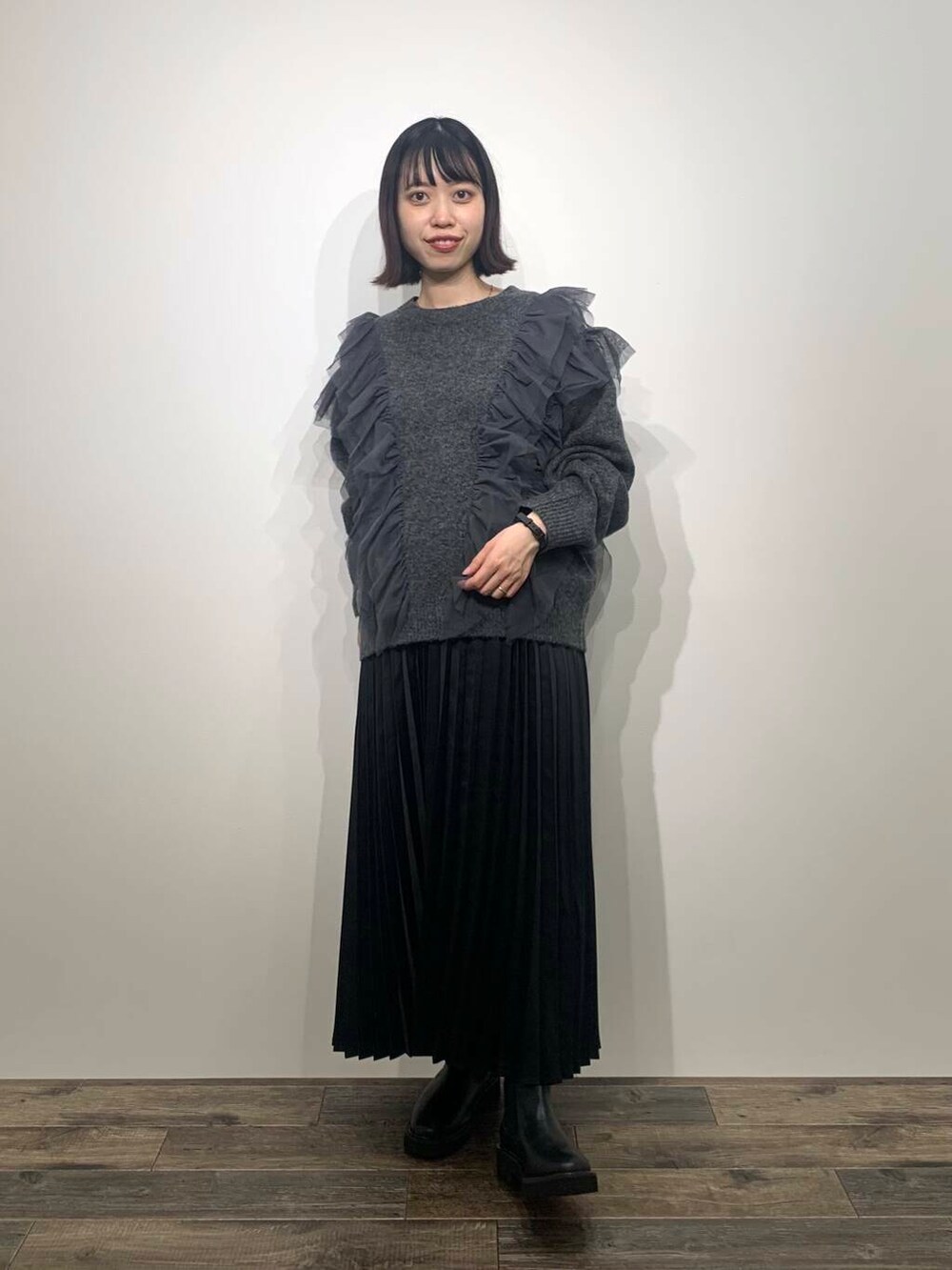 ブラック系のブーツ、グレー系のニット/セーター、ブラック系のスカートを着用したレディースの秋コーディネートの2枚目の写真