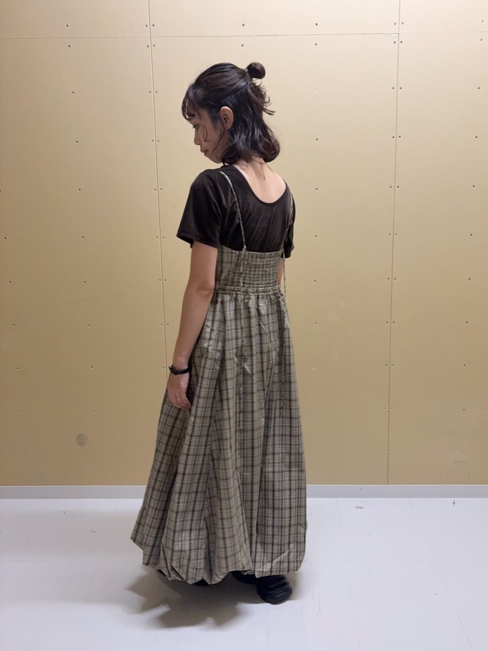 ベージュ系のワンピース、ブラウン系のTシャツ/カットソー、ブラック系のスニーカーを着用したレディースの夏コーディネートの3枚目の写真