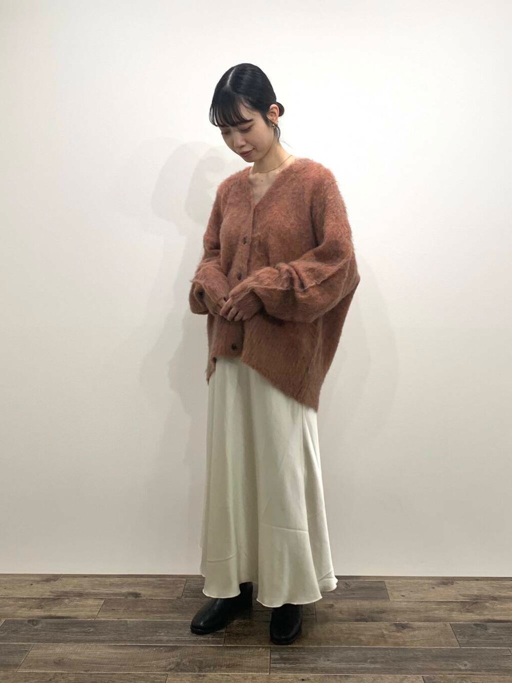 ブラック系のブーツ、ホワイト系のスカート、オレンジ系のカーディガン/ボレロを着用したレディースの秋コーディネートの3枚目の写真