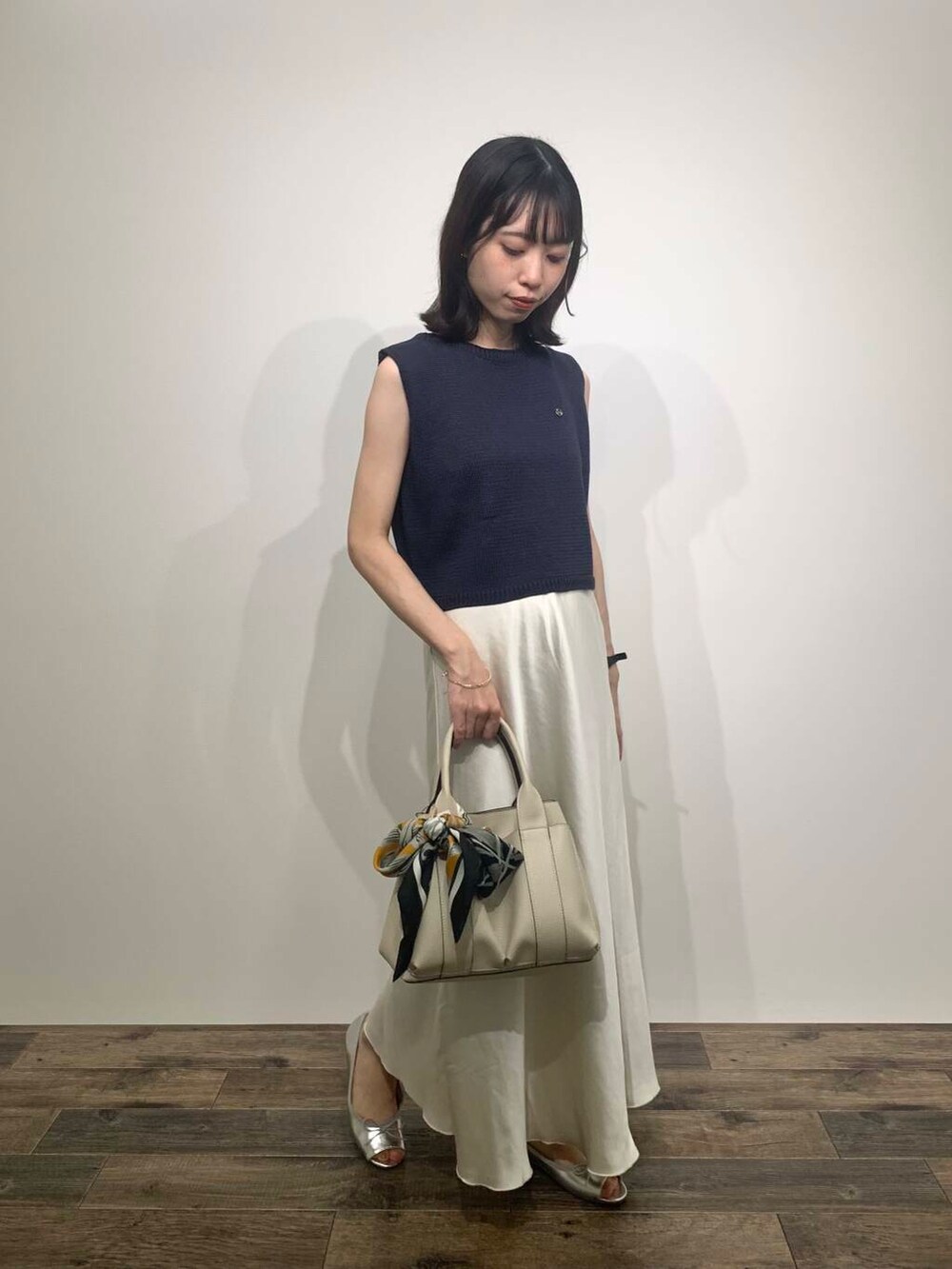 ホワイト系のトートバッグ、シルバー系のパンプス、ブルー系のニット/セーターを着用したレディースの夏コーディネートの3枚目の写真